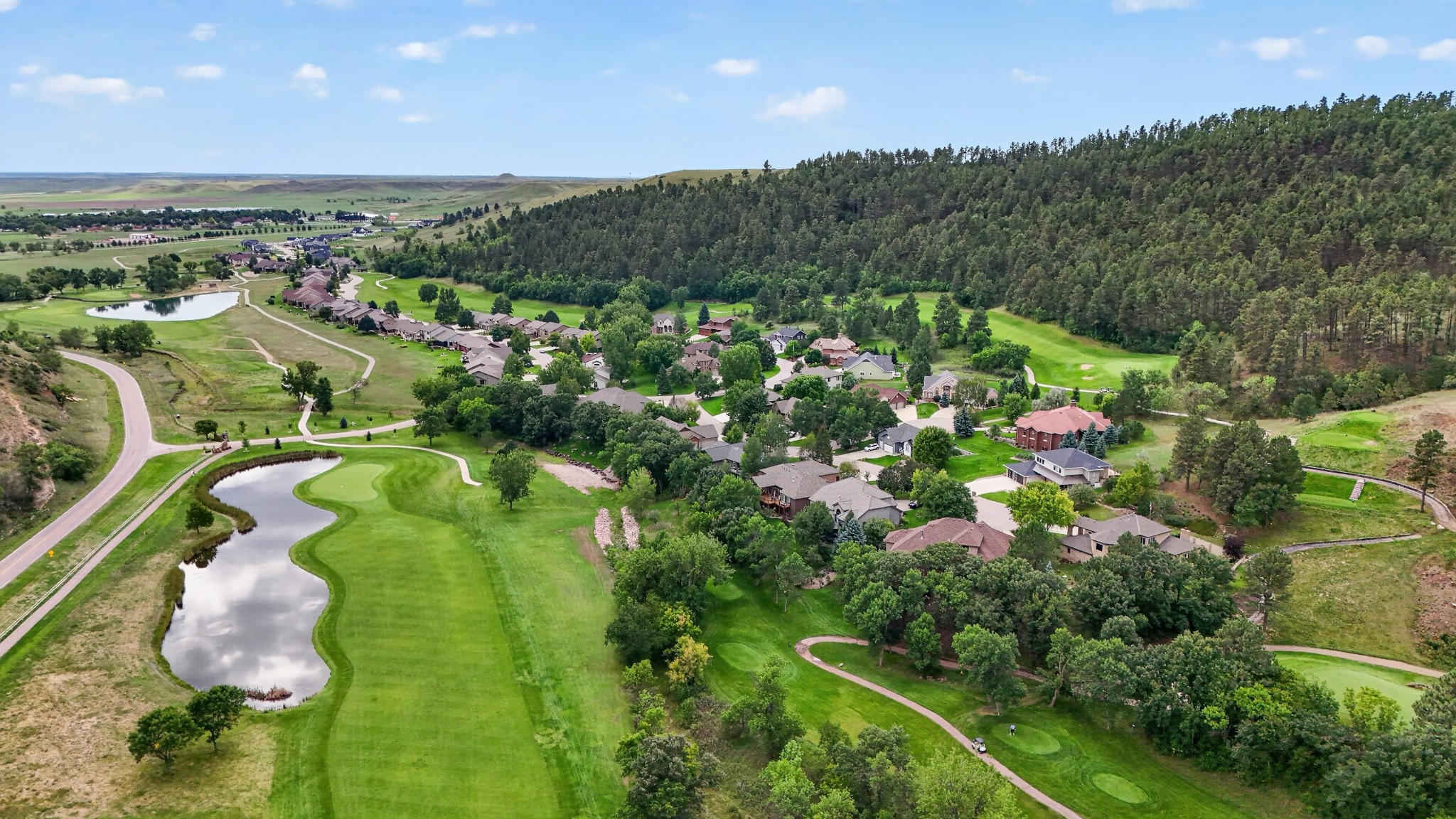 Hart Ranch golf course and pond with homes and Black Hills terrain beyond